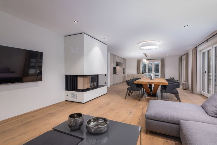 Wohnzimmer einer Wohnung zum Kauf mit Kamin in Rottach-Egern am Tegernsee mit Bergblick.