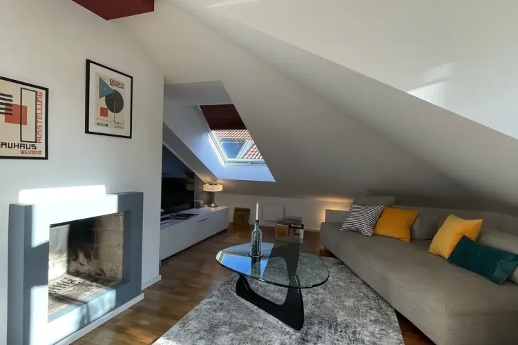 Gemütlicher Wohnbereich mit modernem Kamin in Dachgeschoss-Wohnung zum Kauf in Pullach im Isartal.